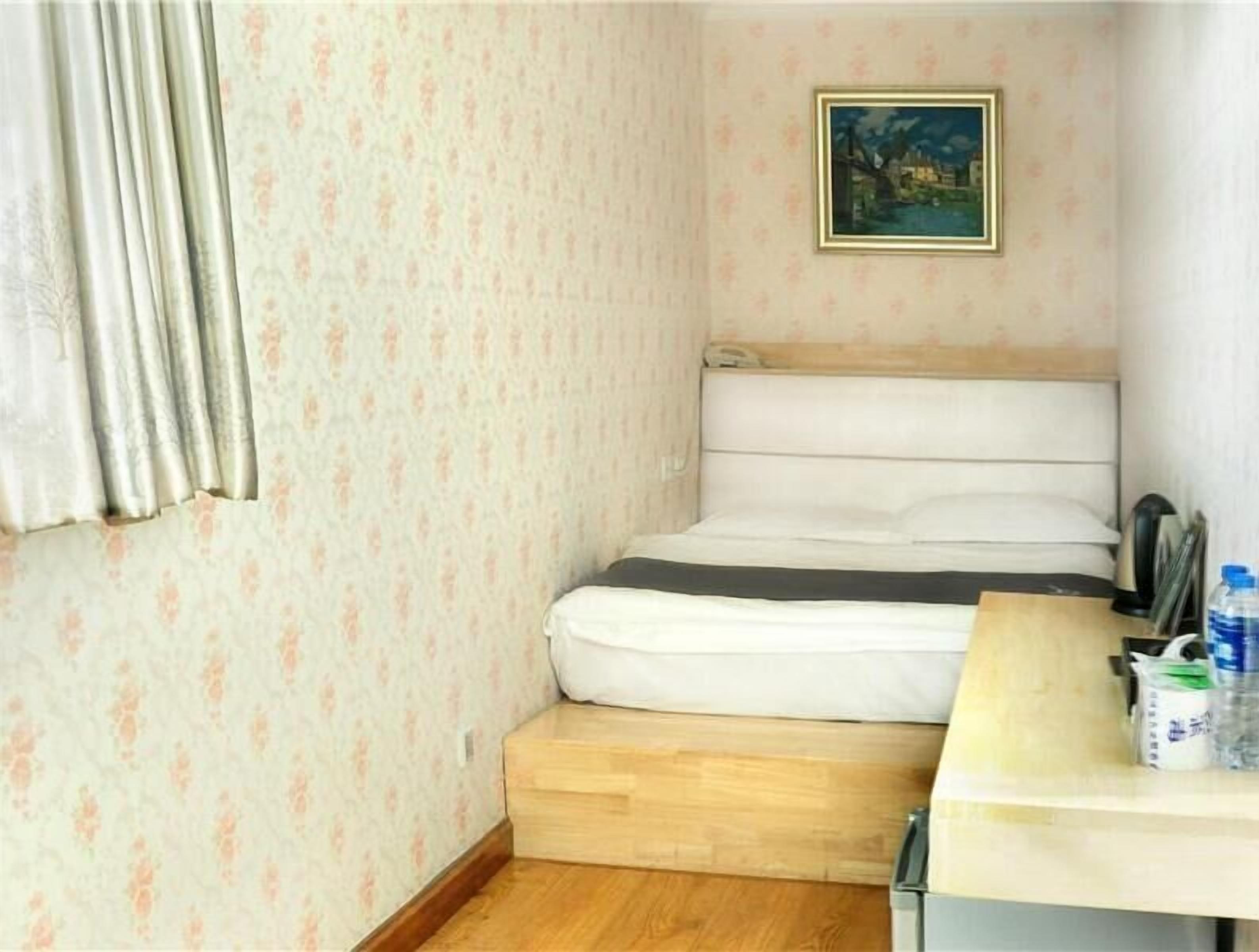 Um quarto pequeno com uma cama, uma escrivaninha de madeira, uma cadeira e um quadro na parede.
