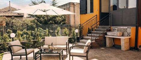 Une terrasse extérieure avec un ensemble de canapés, une table et un grand parasol.