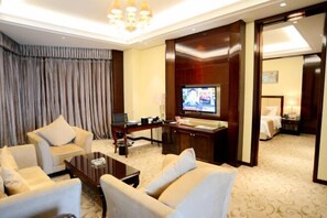 Une chambre d’hôtel équipée d’une télévision, d’un bureau avec un ordinateur, d’un canapé et d’un lit.