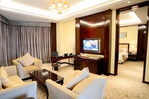 Una habitación de hotel con televisión, escritorio con computadora, sofá y cama.