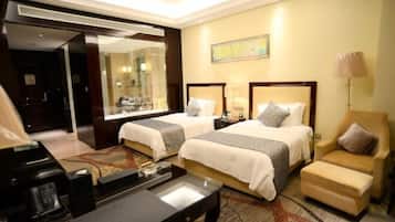 A hotel room with two beds, a desk, a chair, a lamp, and a large mirror.