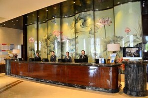 Una recepción con cuatro empleados, un panel decorativo grande y un televisor.