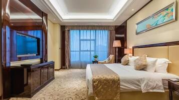A hotel room with a large bed, a television, a desk, and a window with curtains.