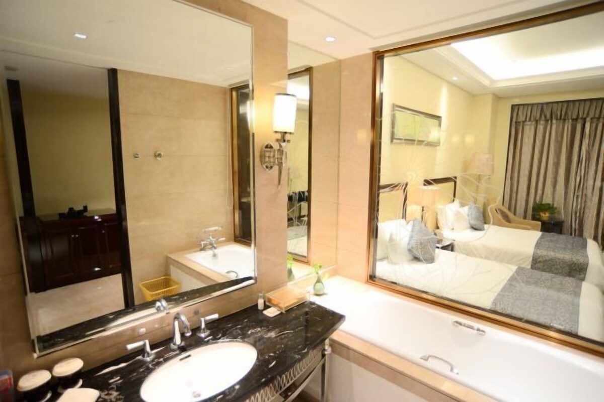 Un baño de hotel con un espejo grande, un lavamanos y una bañera.