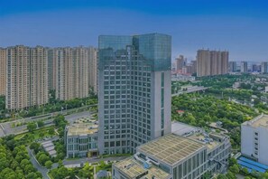 A high-rise building with a glass facade, surrounded by other residential buildings and greenery. - Jinyue International Hotel Jinjiang (Jingjiang)