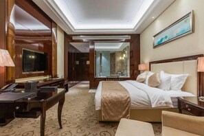 Habitación de hotel con cama, escritorio y un espejo grande.