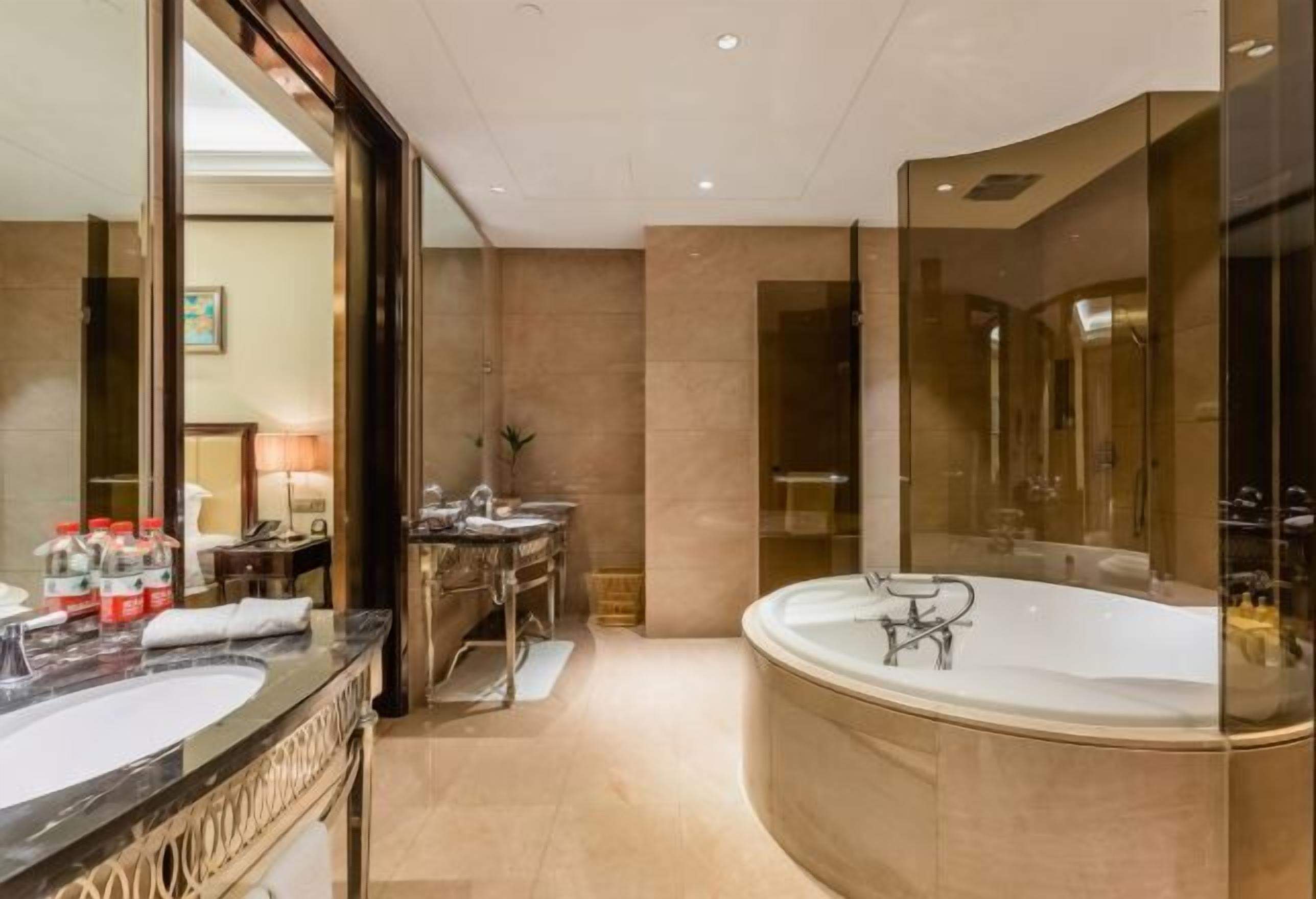 Een luxe badkamer met een ruime badkuip, twee wastafels en een grote spiegel.