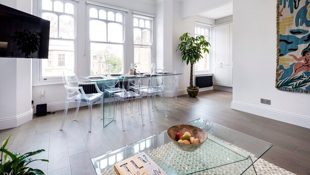 A spacious room with large windows, a glass table, clear chairs, and a potted plant. - Modern and Bright Highgate Gem (London)