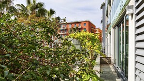 Un sendero estrecho bordeado por abundante vegetación y edificios con balcones.