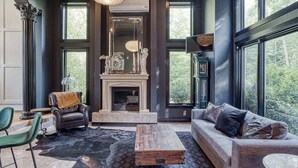 Een moderne woonkamer met een open haard, grote ramen en een stenen vloer.