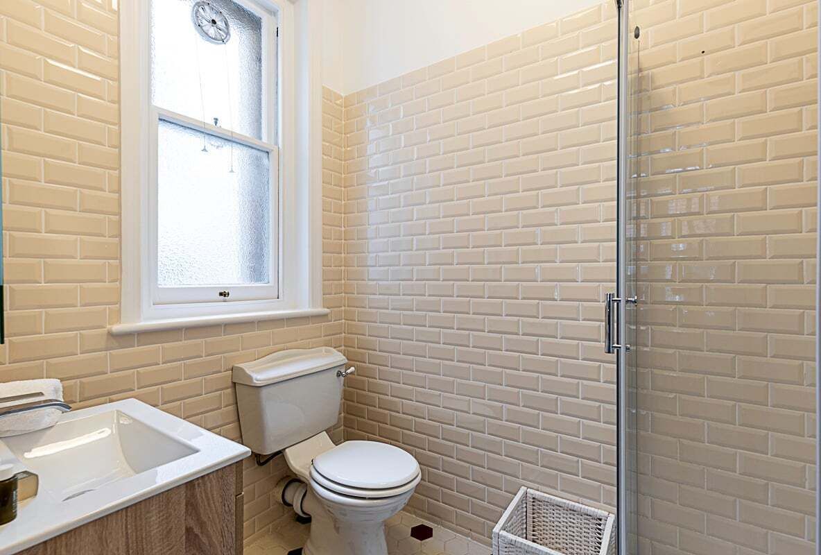 A bathroom with a toilet, sink, and a window.