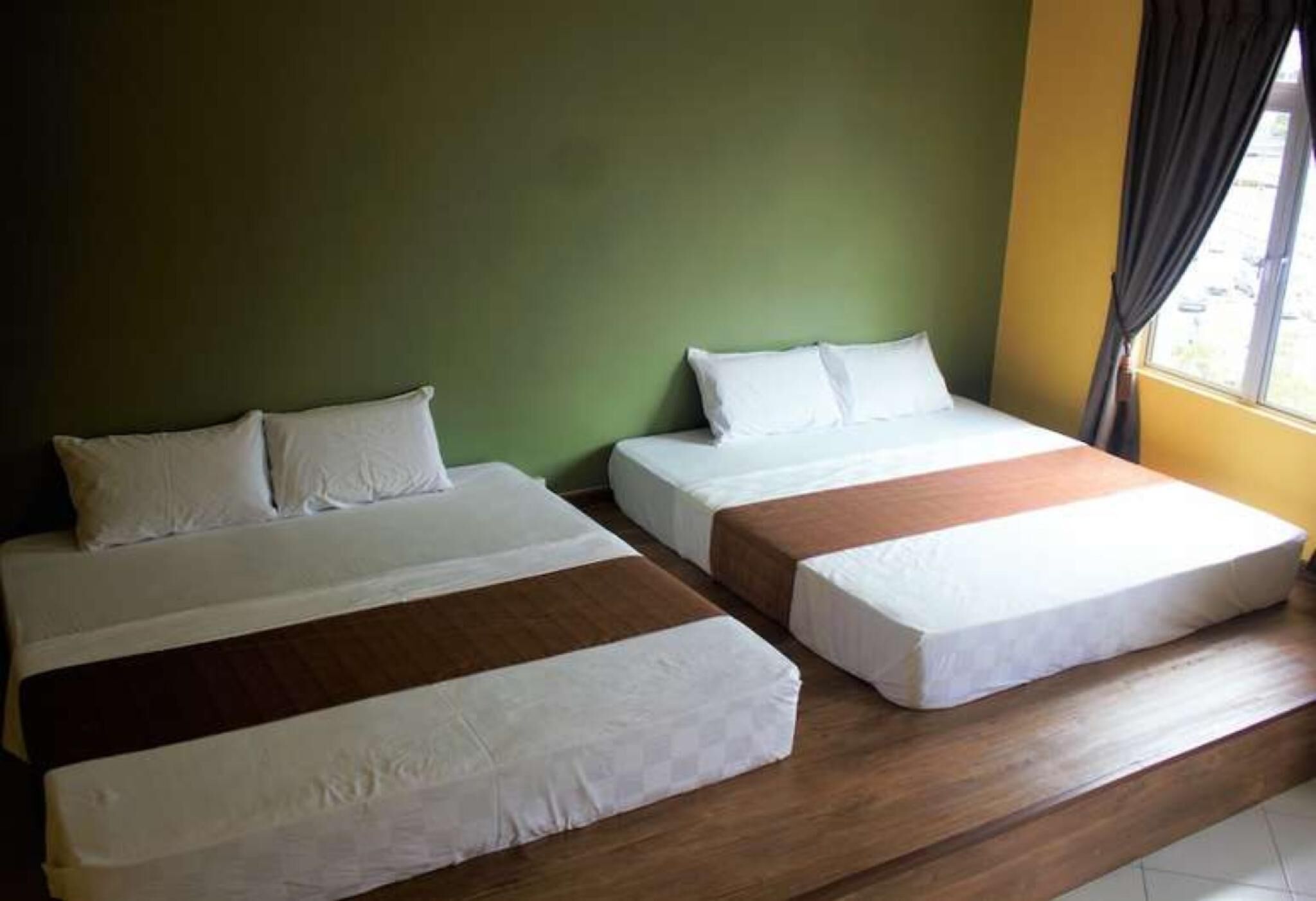 Una habitación con dos camas, cada una con ropa blanca y cabeceras de madera.