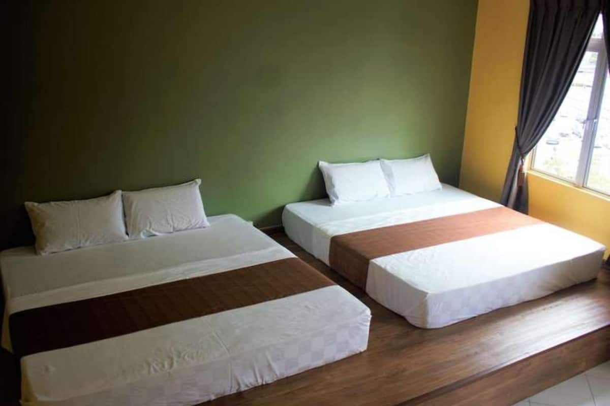 A room with two beds, each with white bedding and wooden headboards.