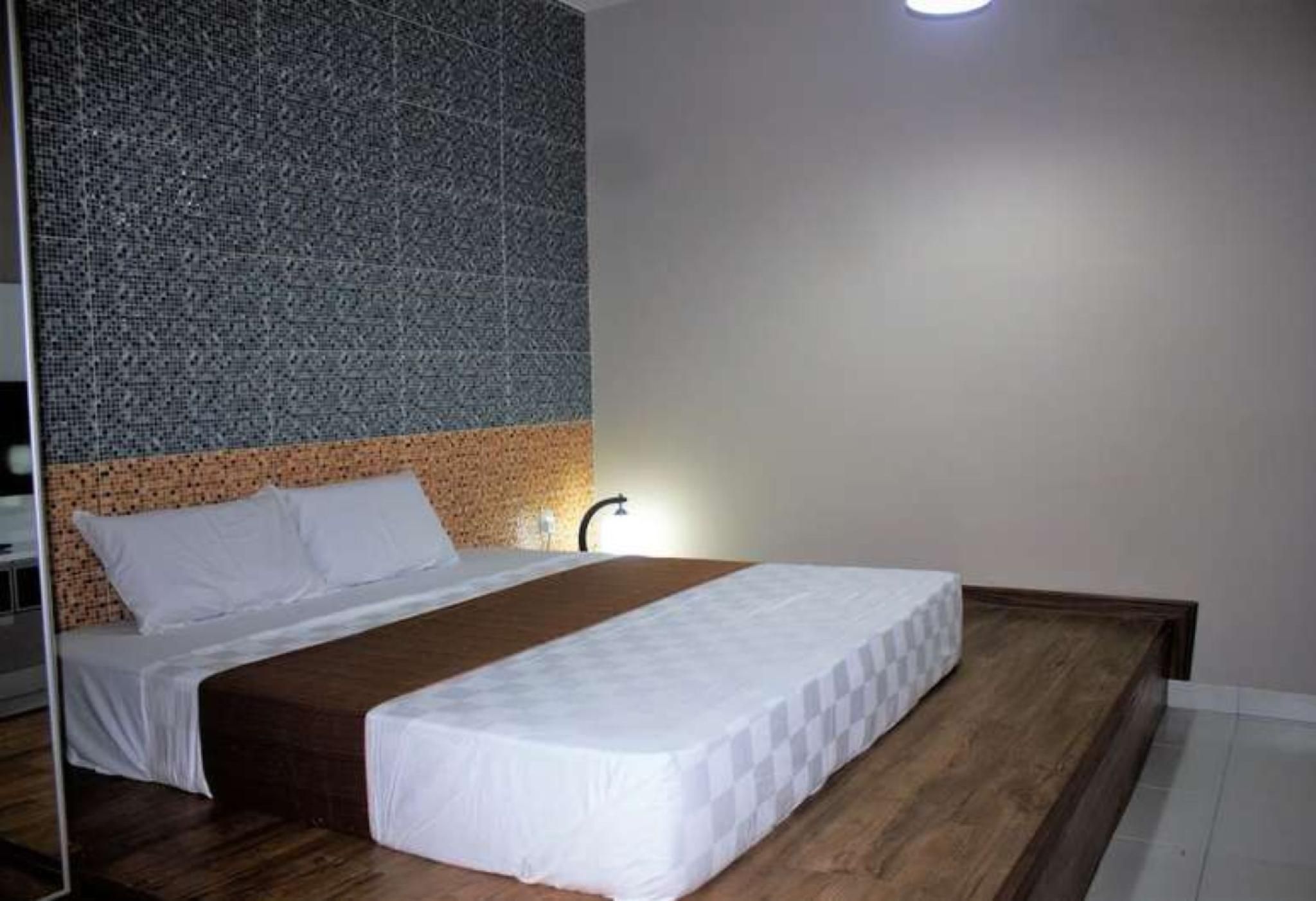 A bedroom with a bed, a headboard, a nightstand, and a wall with a textured pattern.