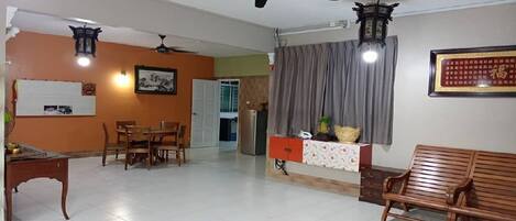 A spacious living area with a dining table, chairs, a sofa, and a ceiling fan.