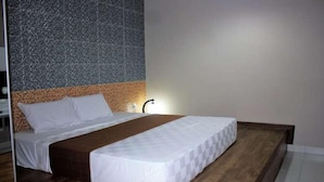 Una habitación de hotel moderna con una cama de madera, un muro con textura y un diseño sencillo.