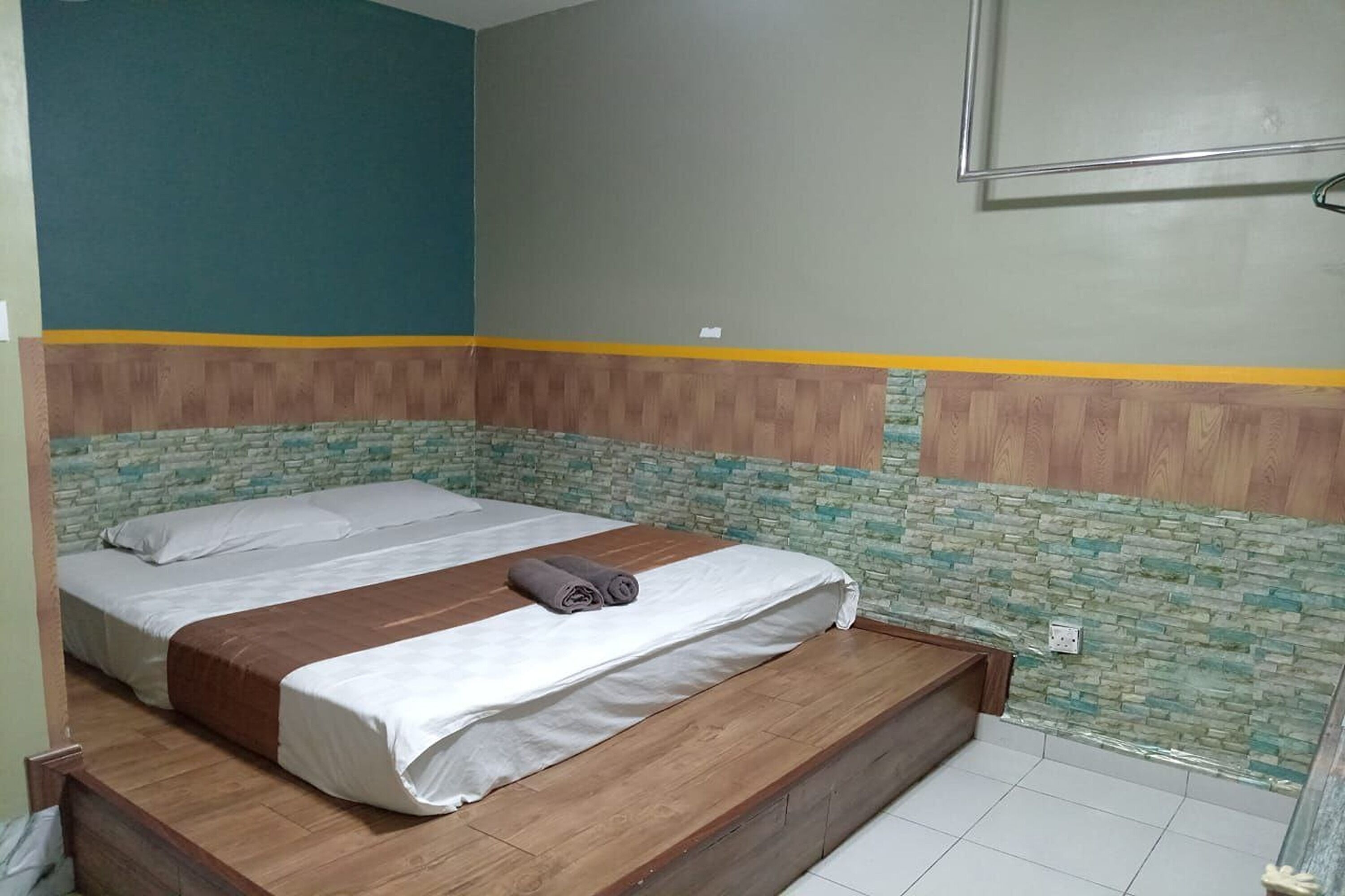 A double bed with a wooden headboard, a small bedside table, and a wall-mounted TV.