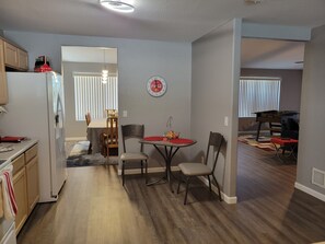 A compact kitchen with a refrigerator, wooden cabinets, and a dining area with a table and chairs.