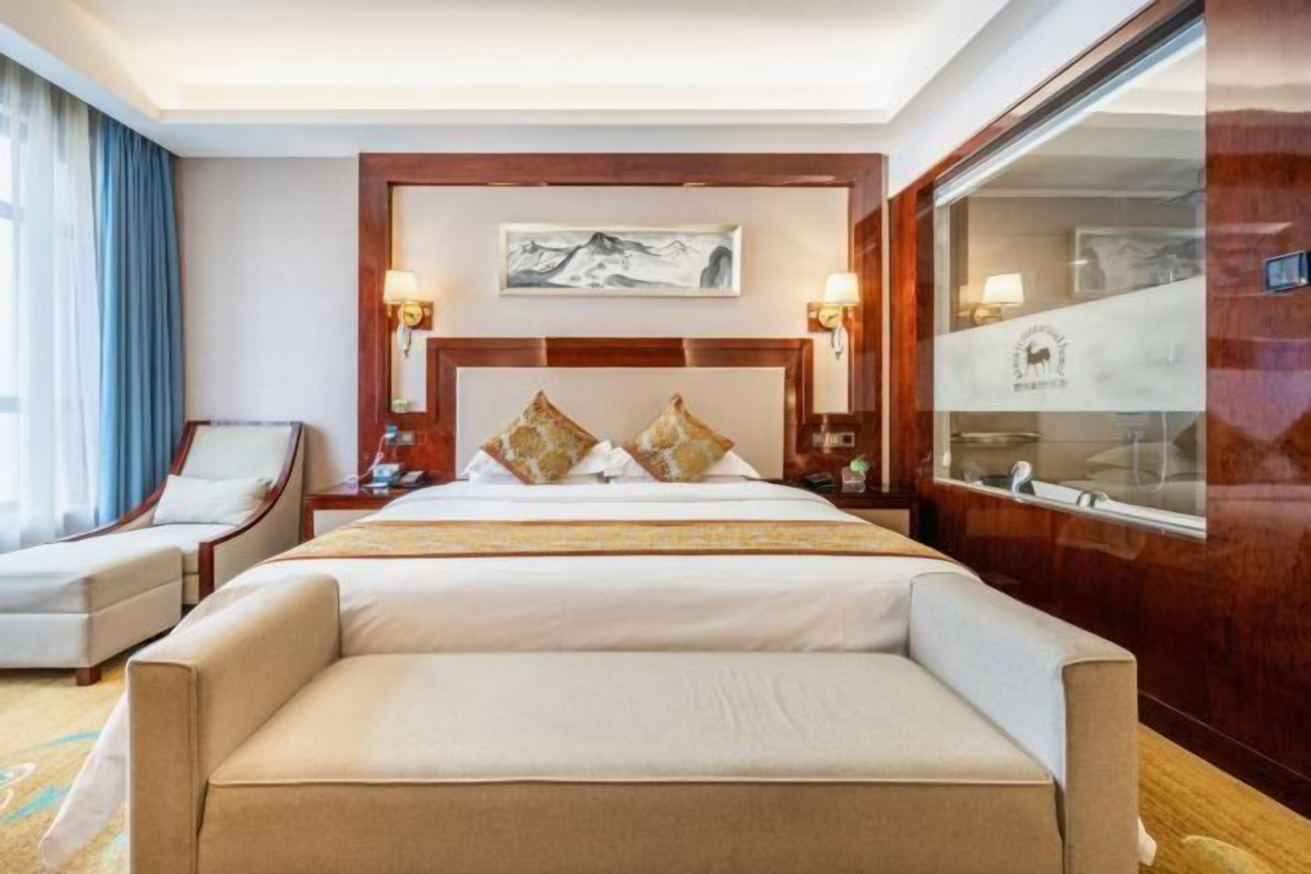 A hotel room with a large bed, two bedside tables, a chair, and a large window with curtains.