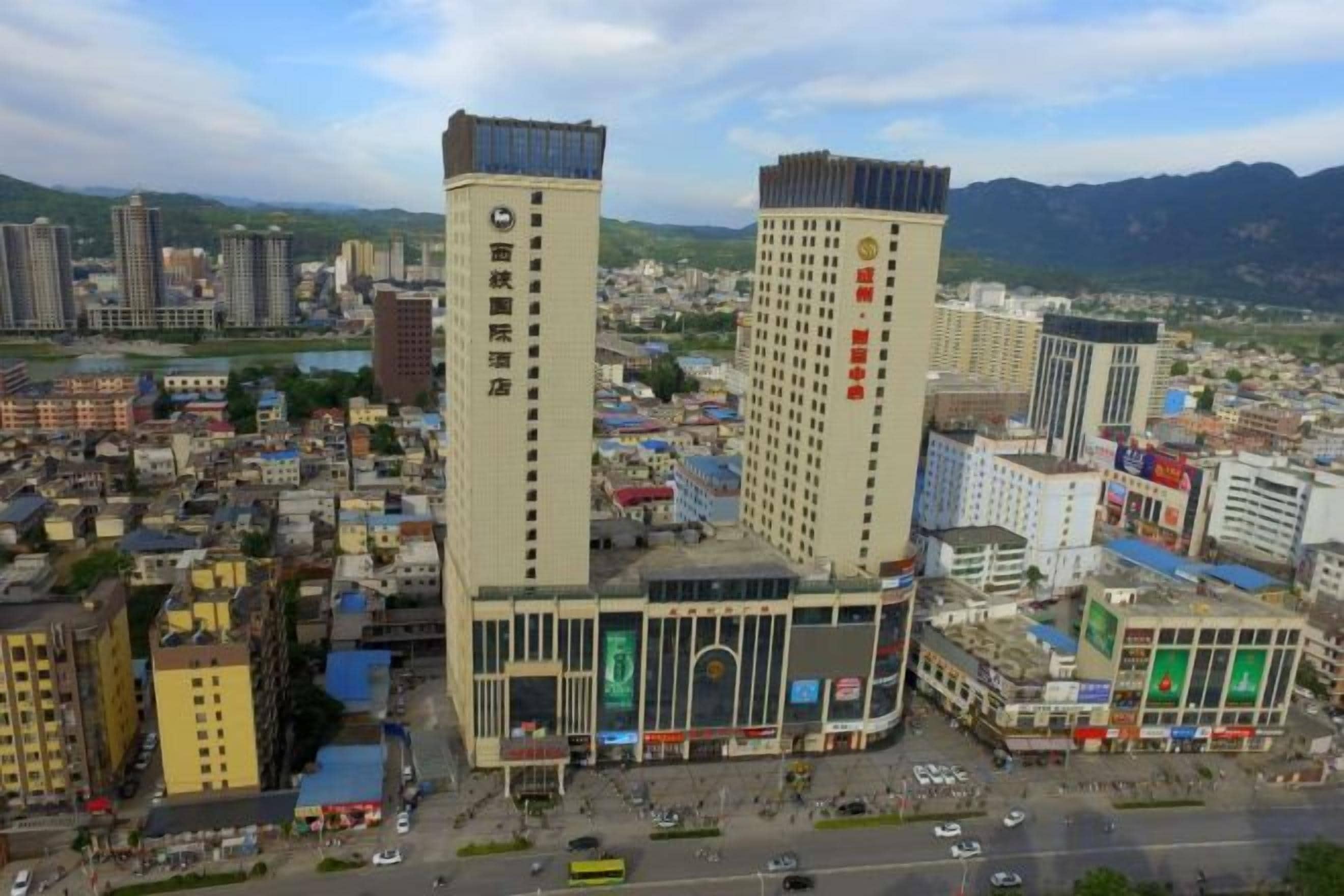 A cityscape with two prominent high-rise buildings, one with a vertical sign and the other with a horizontal sign.