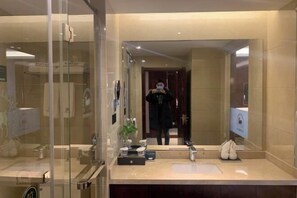A modern hotel bathroom with a glass shower enclosure, a large mirror, and a vanity with a sink and towel rack. - Xixia International Hotel (Cheng County)