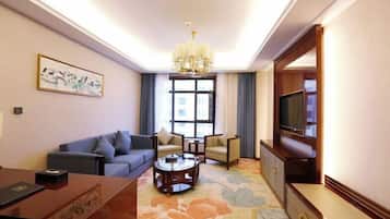 Una sala de estar con sofá, sillones, una mesa de centro, televisor y candelabro.