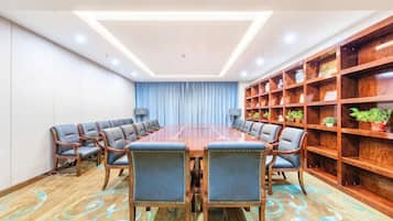 Ein Konferenzraum mit einem langen Tisch, Stühlen und einem Bücherregal.