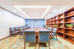 Un salón de conferencias con una mesa larga, sillas y una estantería.