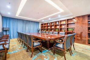 A conference room with a large wooden table, chairs, a blue curtain, and a bookshelf with various items. - Xixia International Hotel (Cheng County)