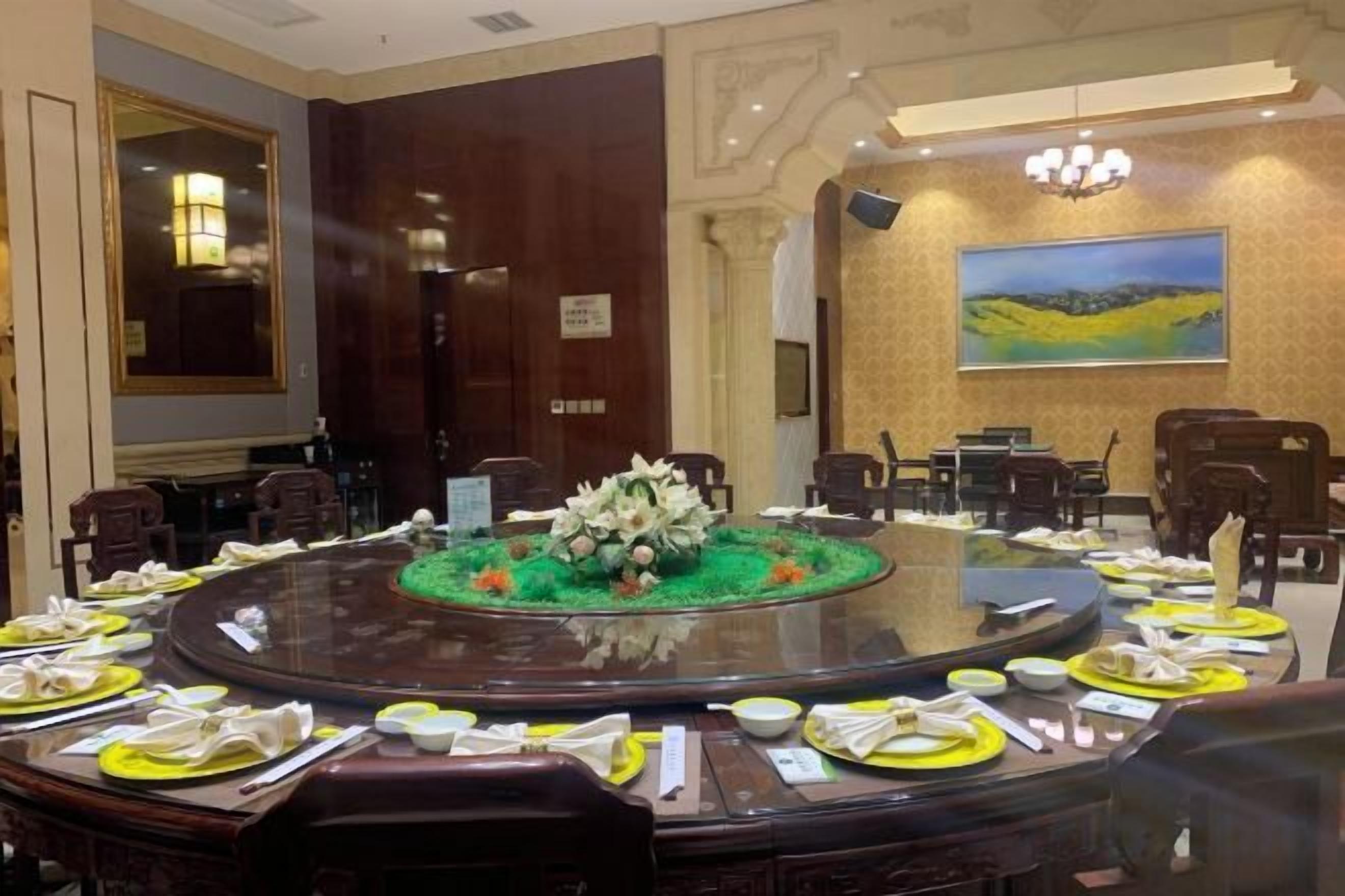 A conference room with a round table, chairs, and a floral centerpiece.