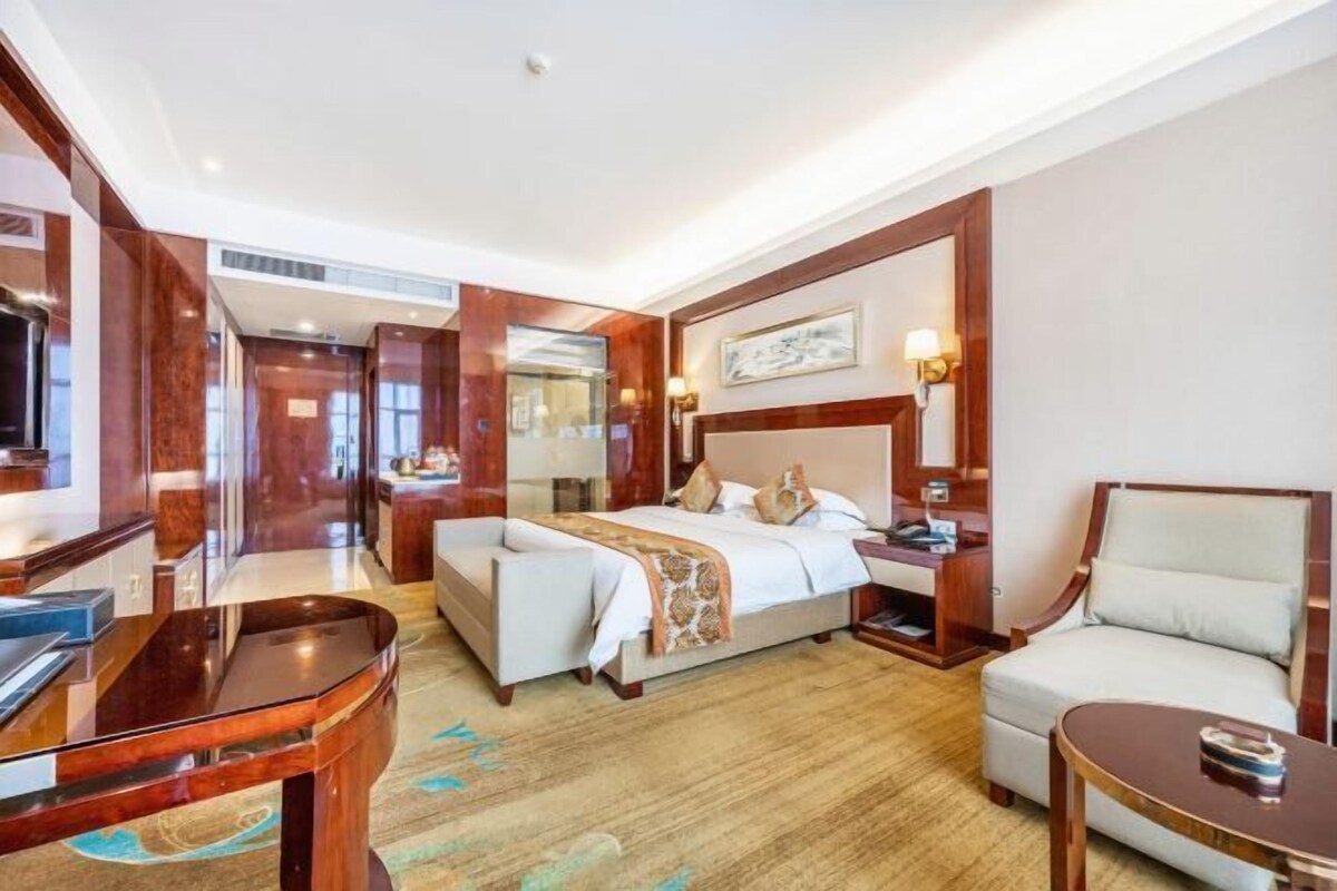 A hotel room with a bed, a desk, a chair, and a television.