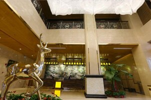 A lobby with a large chandelier, a deer sculpture, and a reception desk.
