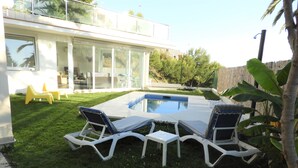 A modern outdoor pool area with white lounge chairs and a rectangular pool.