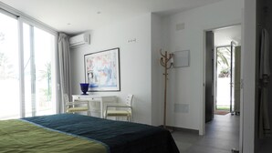 A bedroom with a bed, a desk, chairs, and a coat rack.