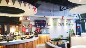 A modern reception area with a wooden counter, a digital screen, and a wall with decorative elements and a sign. - Greentree Inn Zhangjiakou Xuanhua Boju Business Hotel (Zhangjiakou)