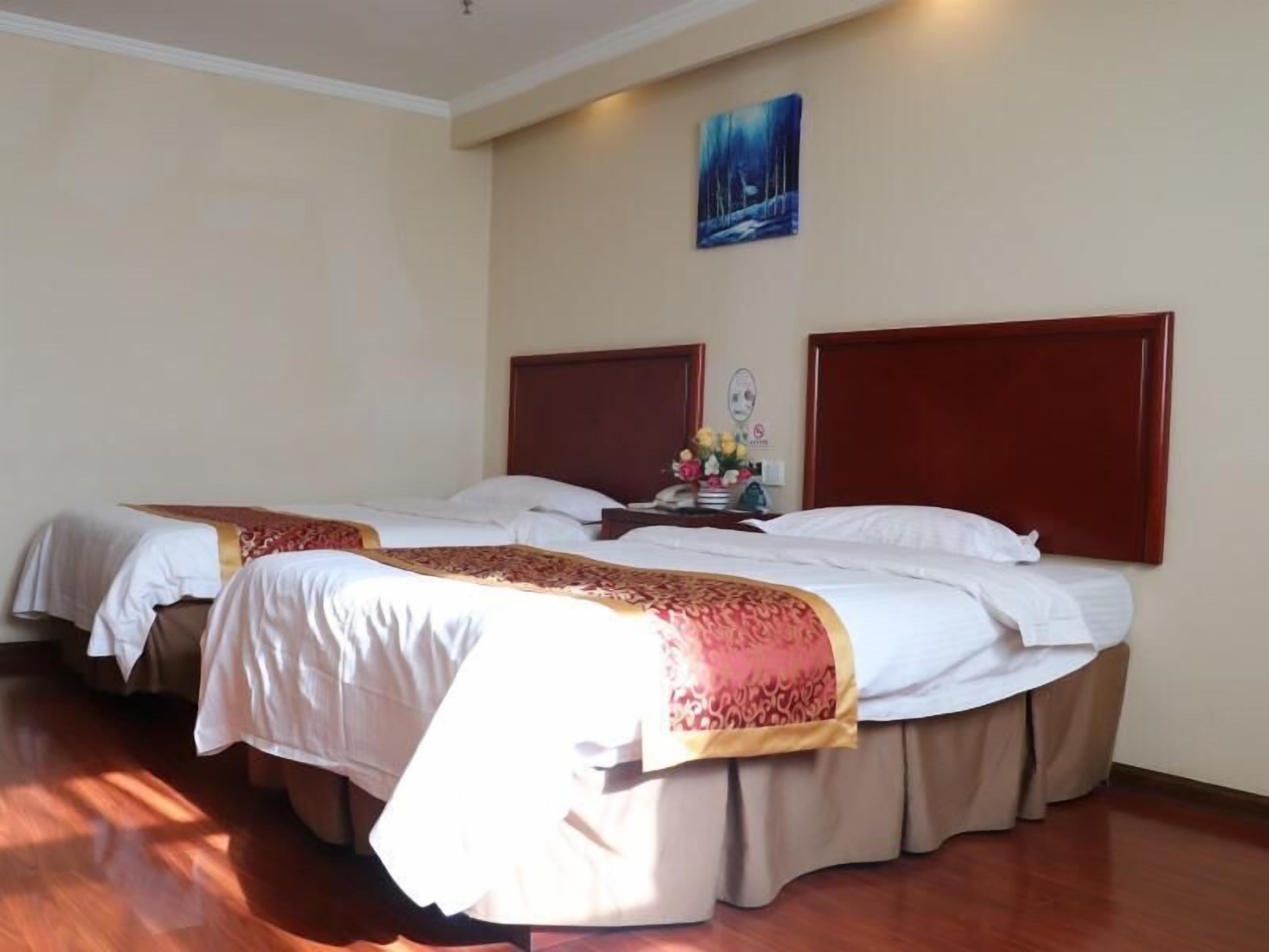 A hotel room with two beds, a nightstand with a lamp, and a painting on the wall.