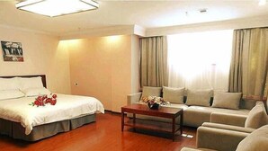 A hotel room with a bed, a sofa, a coffee table, and a window with curtains. - Greentree Inn Zhangjiakou Xuanhua Boju Business Hotel (Zhangjiakou)