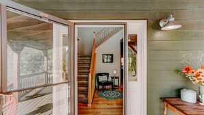 A wooden staircase leading to a second floor, a small table with a vase of flowers, and a door with a glass panel. - Animas River House - 22 acres of Riverfront with Amazing Views-20 mins to skiing (Durango)
