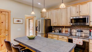 A modern kitchen with granite countertops, stainless steel appliances, wooden cabinets, and pendant lighting. - Animas River House - 22 acres of Riverfront with Amazing Views-20 mins to skiing (Durango)
