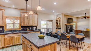 A spacious kitchen with wooden cabinets, a large island, and modern pendant lighting. - Animas River House - 22 acres of Riverfront with Amazing Views-20 mins to skiing (Durango)