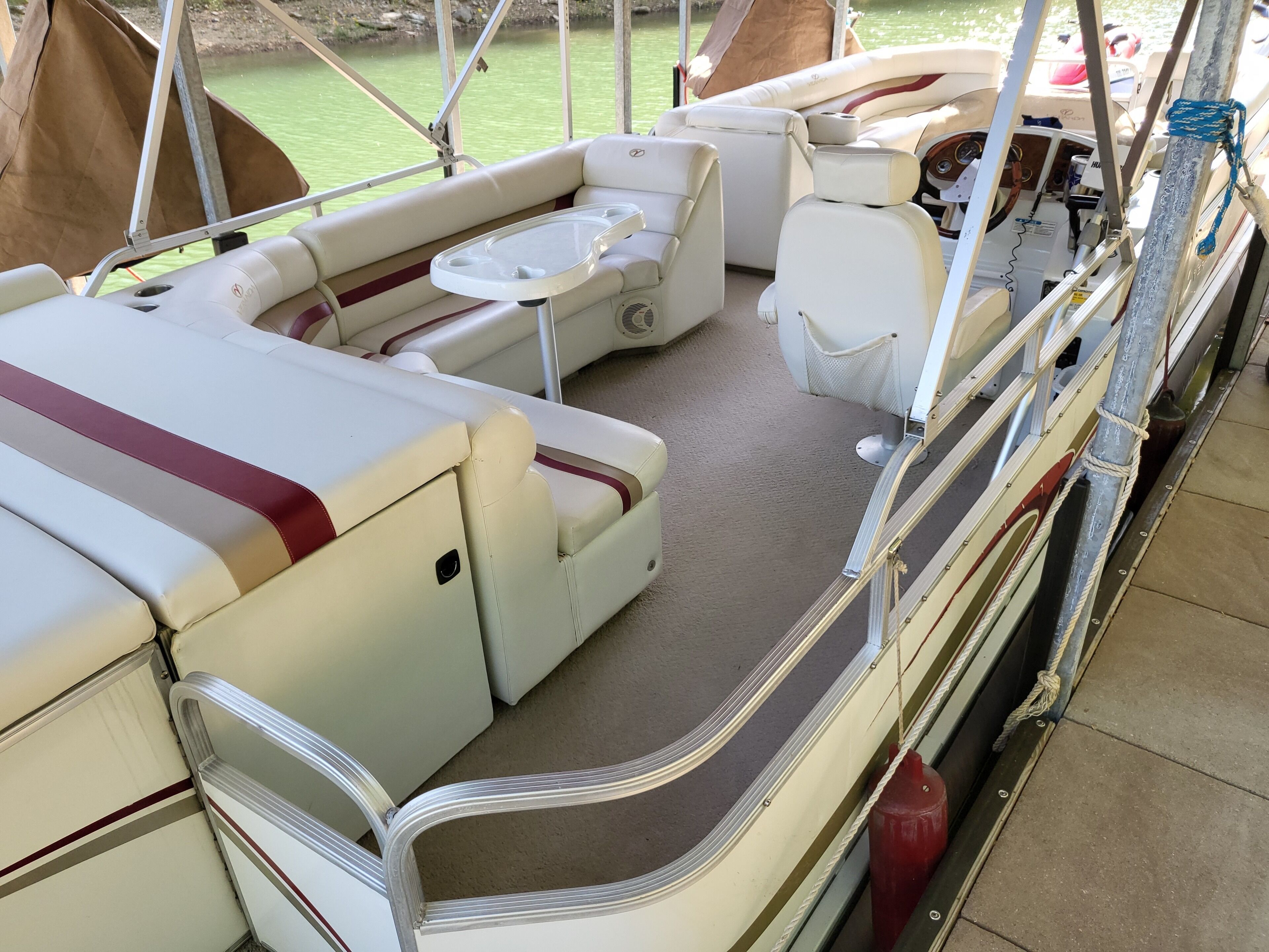 L'intérieur d'un bateau, avec un espace salon doté de sièges rembourrés, une petite table et un volant.