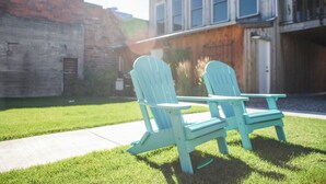 Deux chaises Adirondack bleu clair, accompagnées d’une table de pique-nique, se trouvent dans une cour arrière verdoyante.