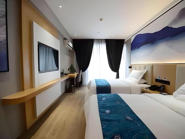 A hotel room with two beds, a desk, and a large window with curtains.