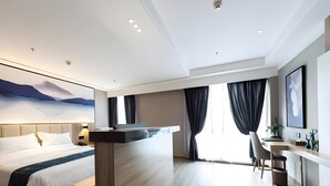 Ett modernt hotellrum med en säng, ett skrivbord och ett stort fönster med gardiner.