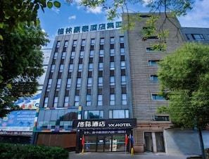 Un edificio de hotel con fachada moderna, ventanas grandes y un cartel que dice 'Vx Hotel'.