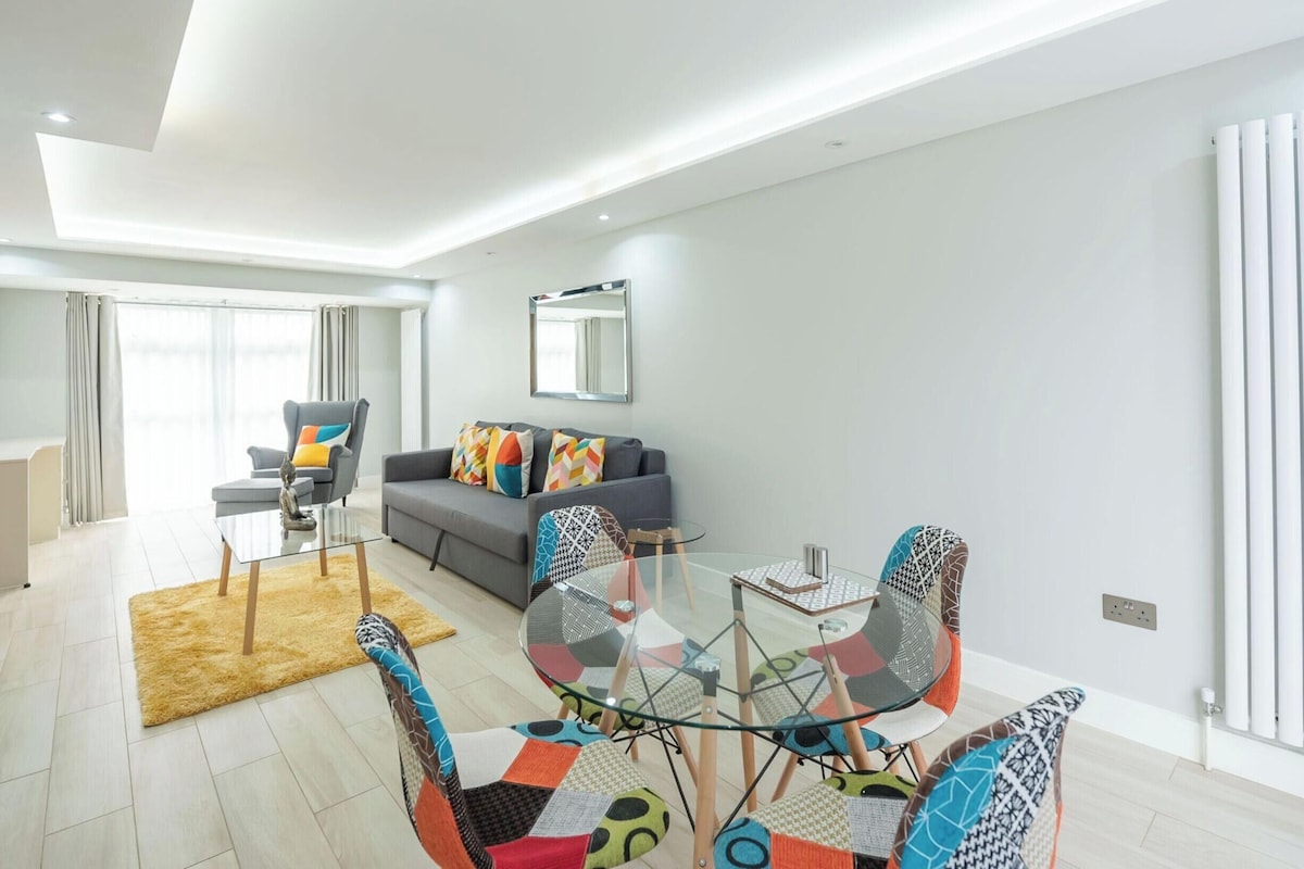 Una sala moderna con un sofá, una mesa de centro de vidrio y sillas coloridas.