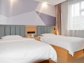 Une chambre d’hôtel avec deux lits, une tête de lit en bois, une table de chevet avec un téléphone et une fenêtre avec des rideaux.