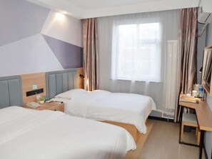 Une chambre d’hôtel avec deux lits, un bureau, une fenêtre avec des rideaux et un mur orné d’un motif géométrique.