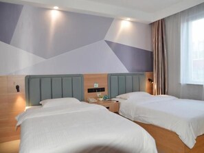 Une chambre d’hôtel avec deux lits, une tête de lit en bois, un téléphone fixé au mur et une fenêtre avec des rideaux.