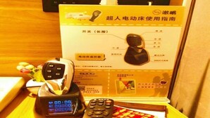 A remote control, a phone, and a box with instructions on a wooden table. - Greentree Inn Taiyuan Hanxiguan Street Wanda Mansion Shell Hotel (Taiyuan)